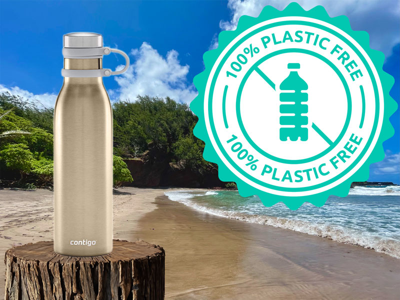 A stainless steel water bottle with a plastic-free label rests on a sandy beach under the Maui sky, surrounded by clouds and lush green foliage—the perfect companion for your private tour of paradise.